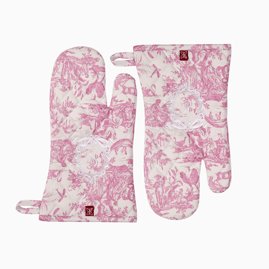 Close-up of a pink Toile de Jouy oven mitt featuring an intricate white embroidered royal emblem.
