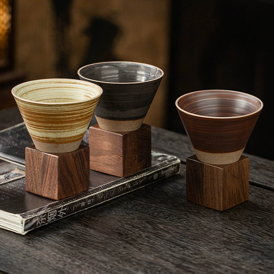 Cone-shaped stoneware cup resting on solid walnut stand
