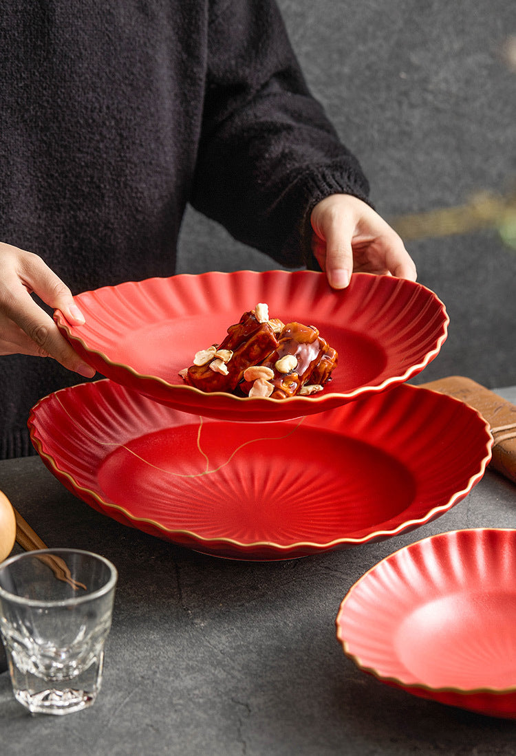 Red ceramic plates on a dark surface with a person holding one of them.