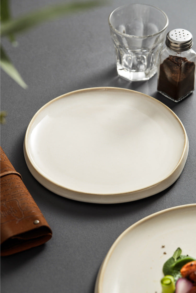 Beige ceramic plate on a dark surface with a glass and salt shaker.