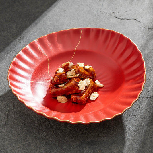 Red plate with roasted cashews on a dark gray surface