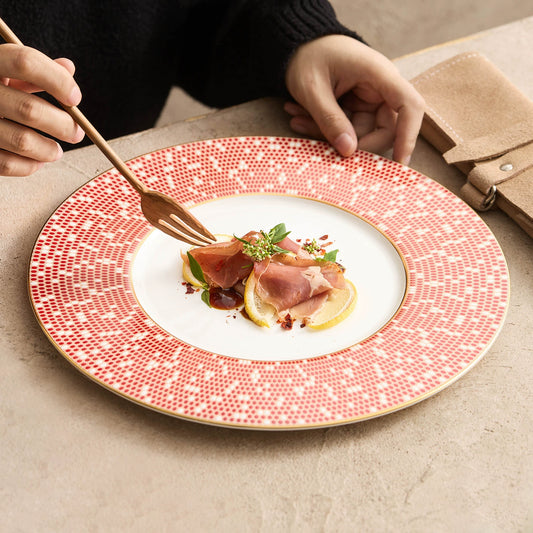 High-contrast culinary plating of prosciutto and lemon on a Golden Red mosaic dish.
