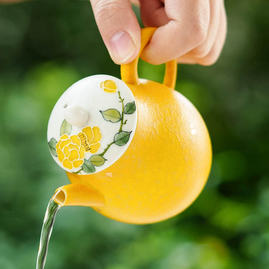 Imperial yellow textured teapot featuring a hand-painted floral lid and green leaves.