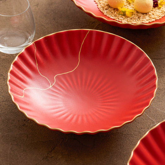 Red ceramic plate with gold rim on a brown surface