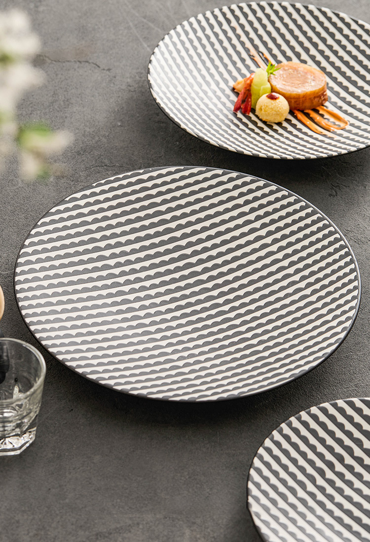 Two patterned ceramic plates on a dark surface with a glass of water.