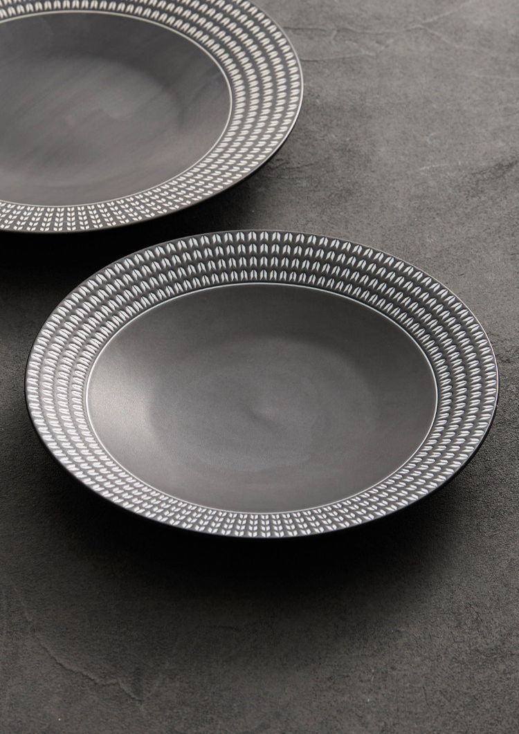 Tactile geometric texture on the rim of a contemporary matte black dinner plate.
