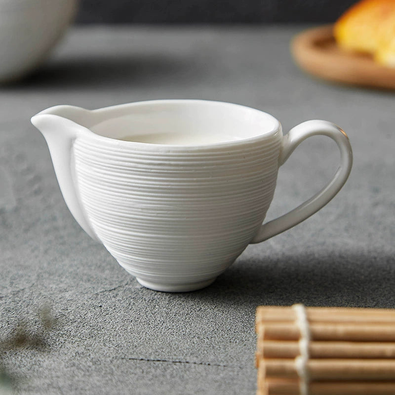Textured ceramic milk pitcher on grey tabletop