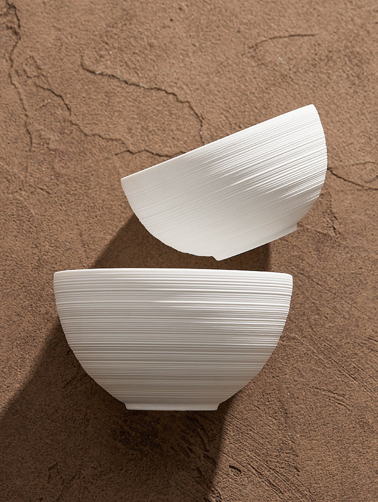 White round bowl with horizontal grooves on wooden table