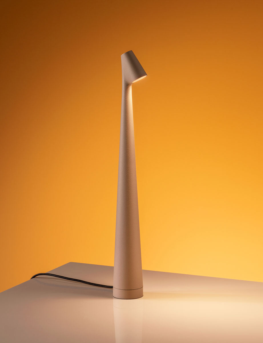 Modern beige table lamp on a reflective surface with an orange background