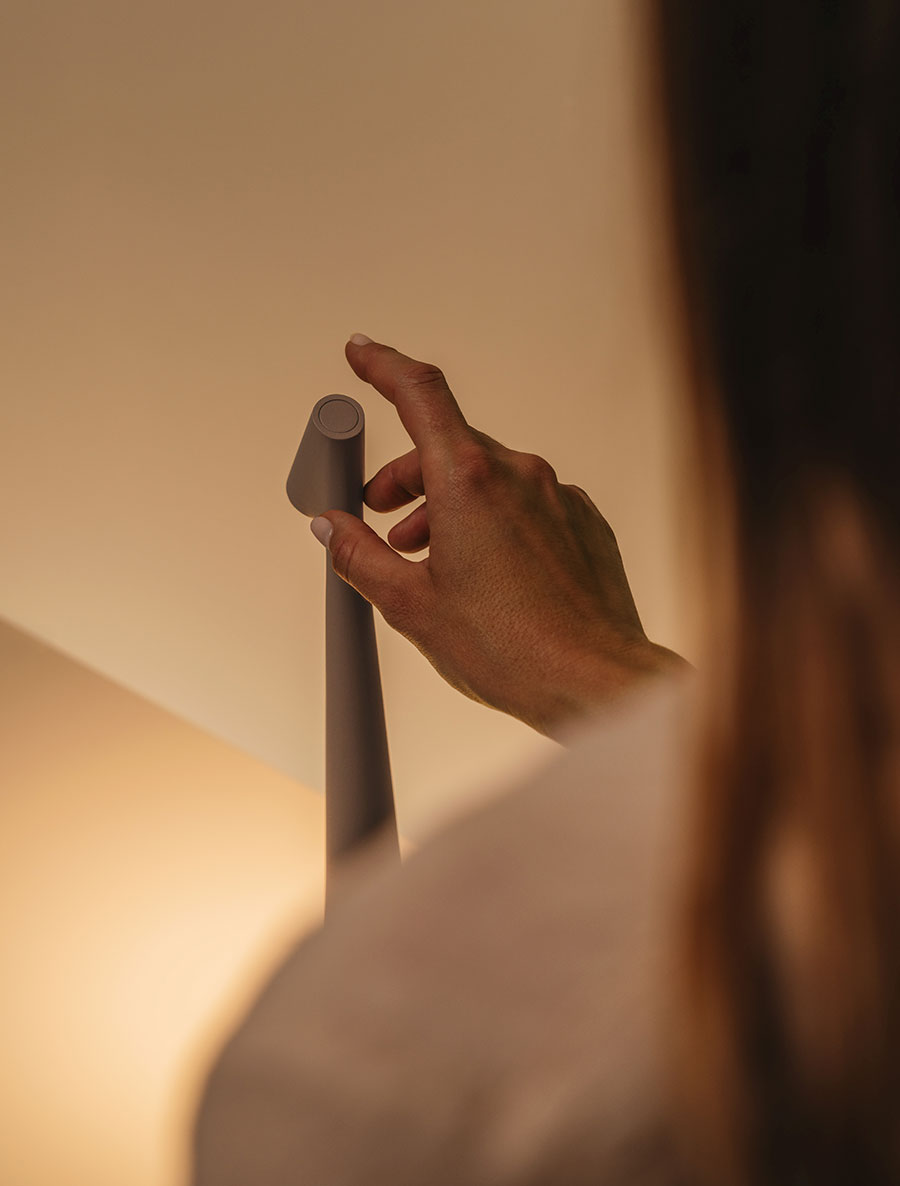 Hand adjusting a lampshade on a soft focus background