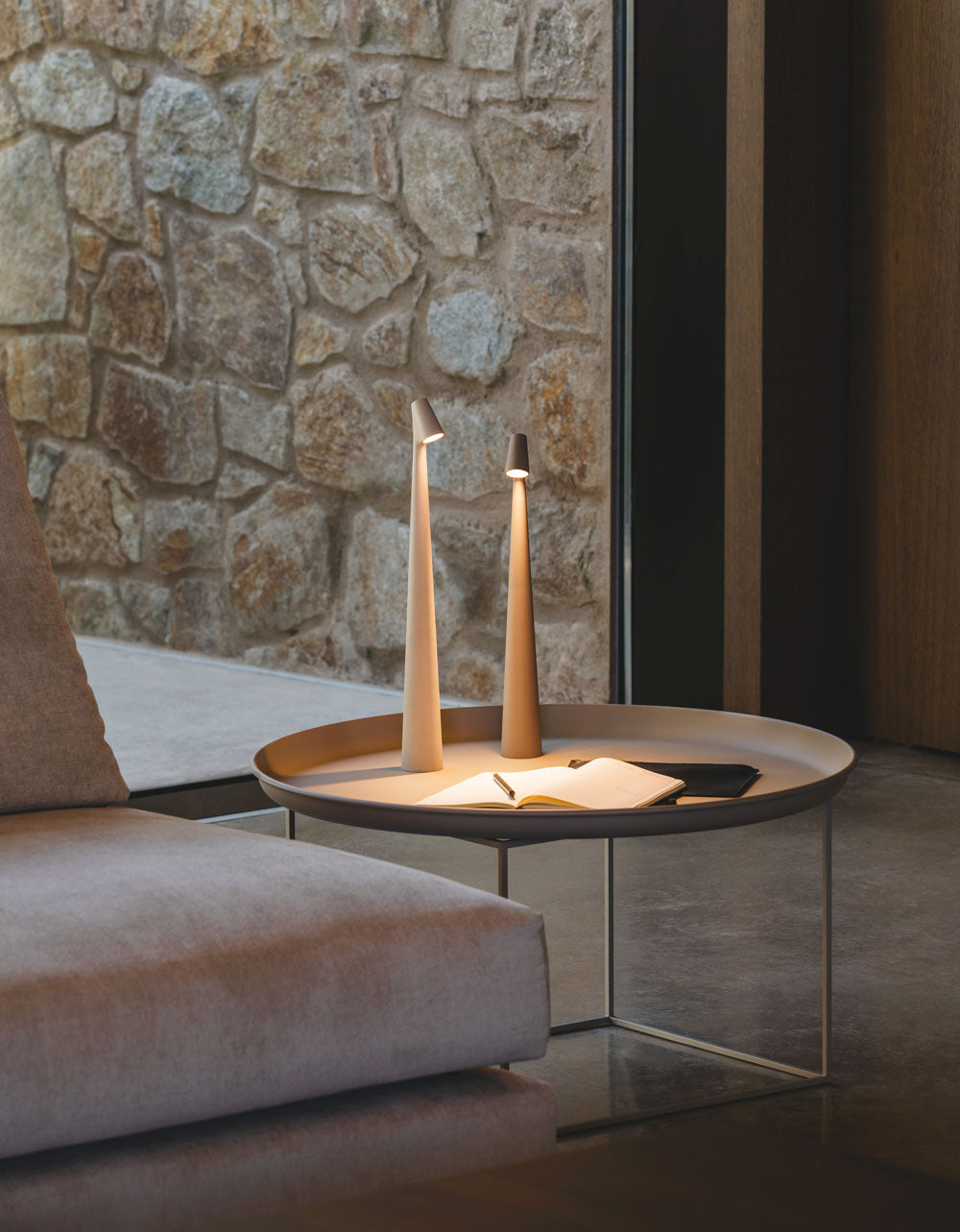 Modern living room with a stone wall, sofa, and round coffee table with decorative items.