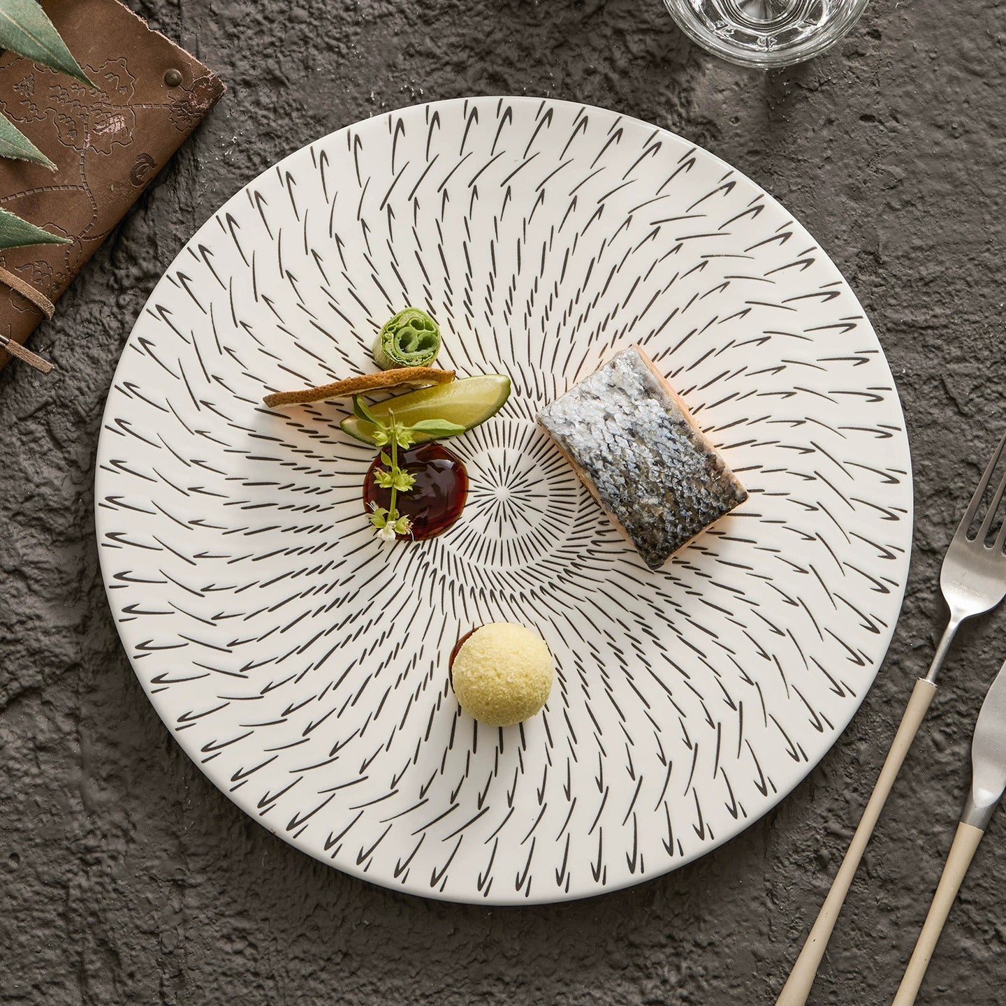 Decorative plate with a dessert on a textured surface with cutlery.