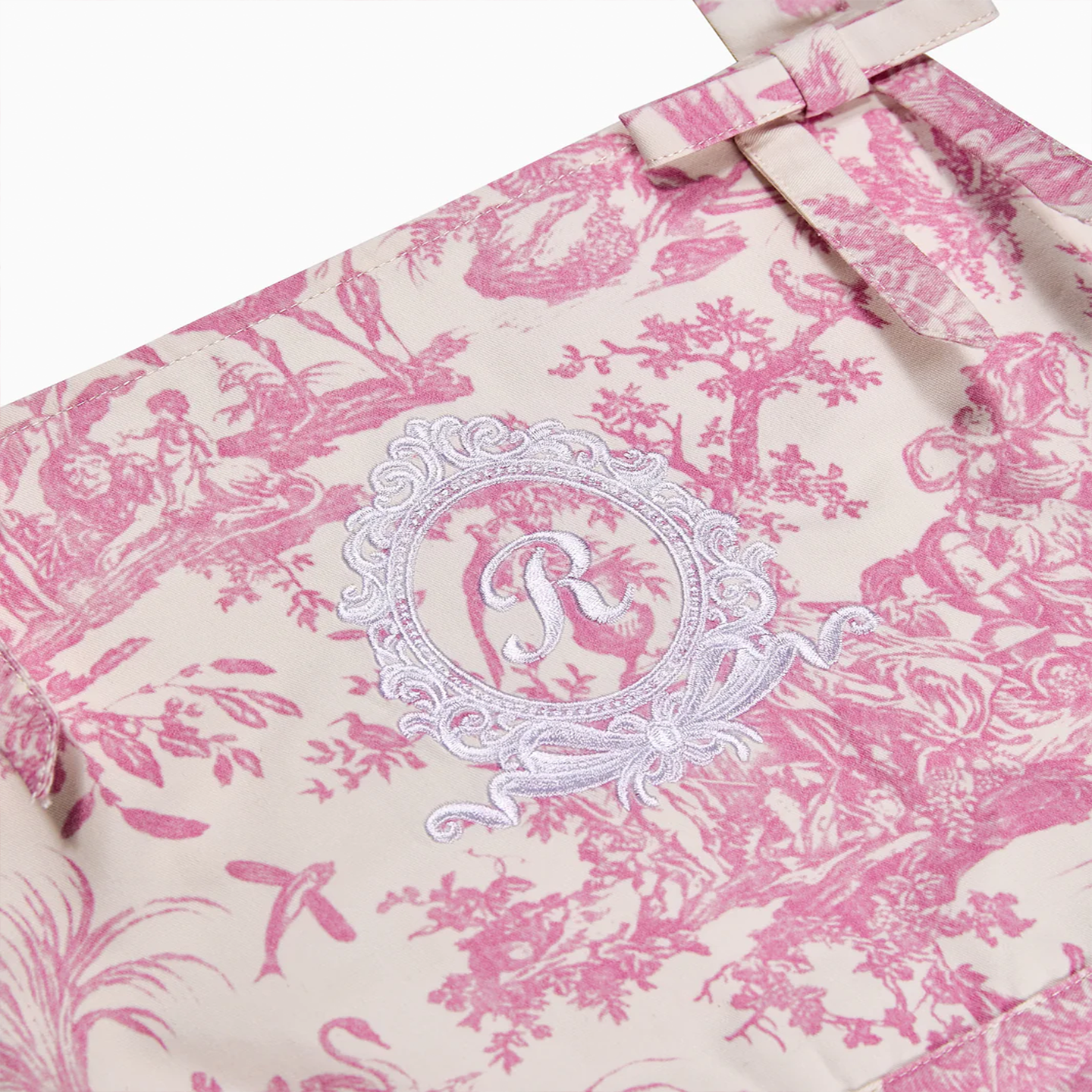 A refined culinary garment featuring sophisticated pink pastoral motifs and high-quality embroidery.