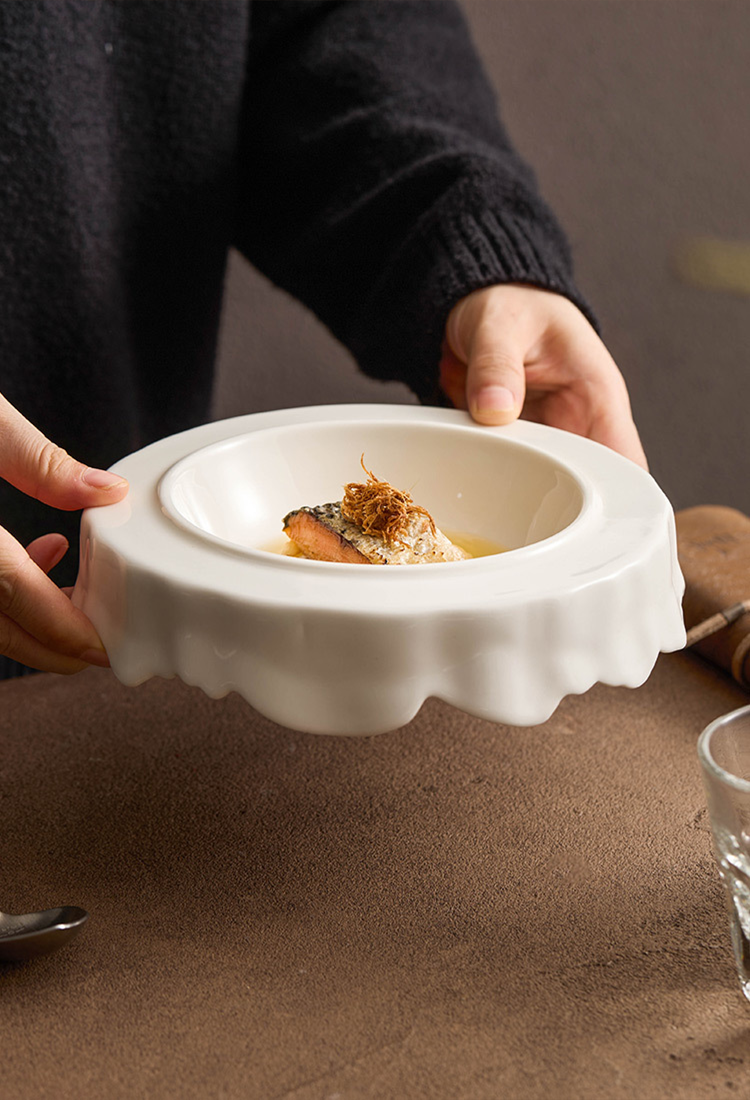 Artistic porcelain plate under warm light on textured tabletop.