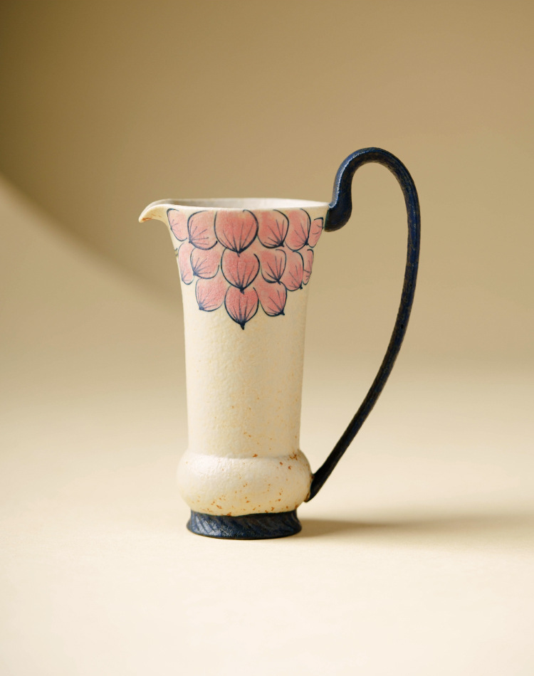 Beige ceramic jug with blue handle and floral art