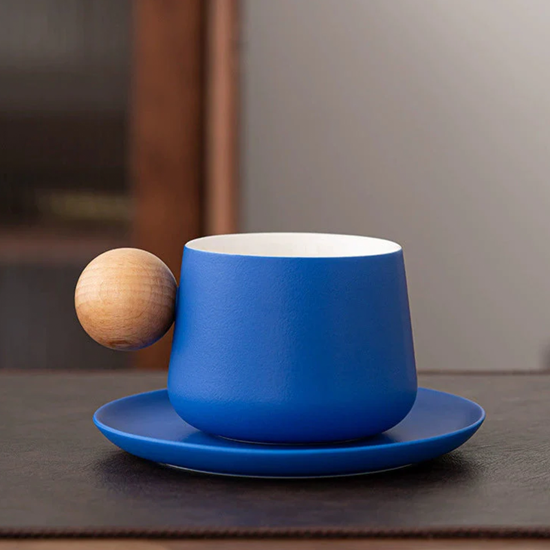 Blue cup and saucer with a wooden ball on a dark surface