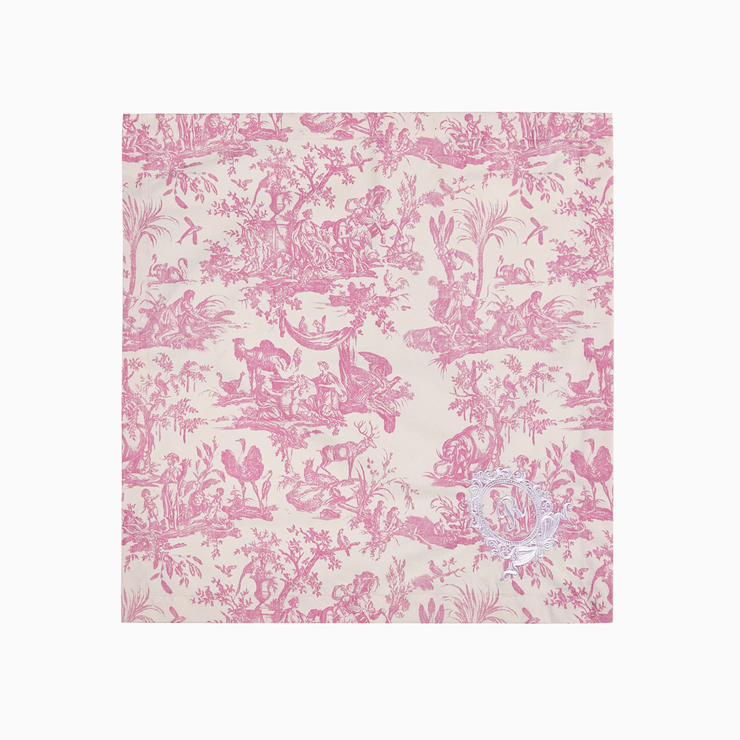 Close-up of four folded pink Toile de Jouy napkins featuring white royal-inspired embroidered emblems.