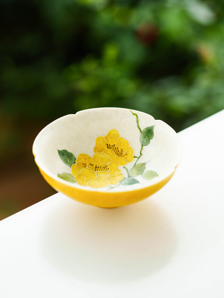 Close-up of hand-painted floral details and green leaf motif on white porcelain.