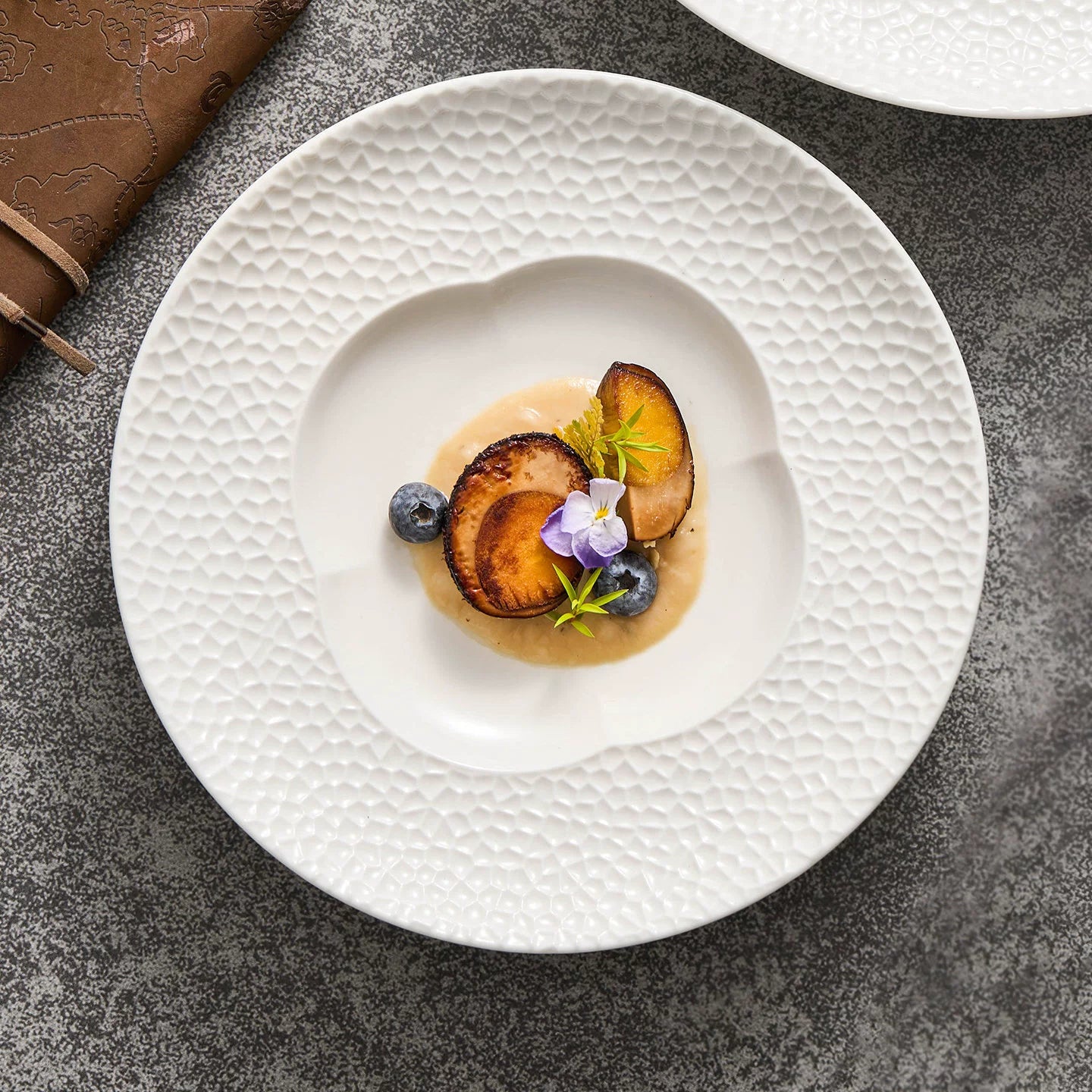 Close-up of the intricate tactile lattice pattern on the rim of a white ceramic plate.
