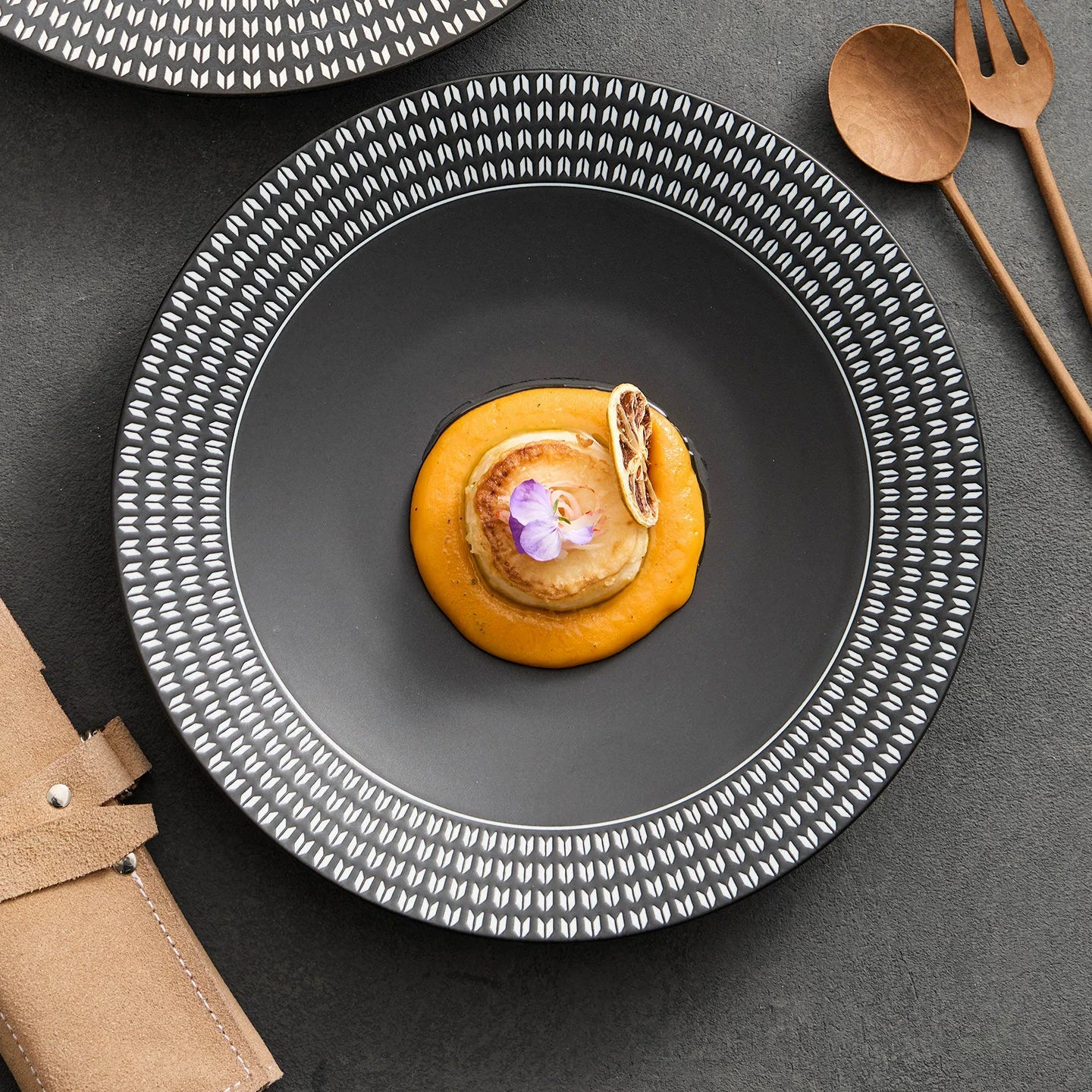 Close-up of the intricate white geometric pattern on the wide rim of a professional-grade ceramic soup plate.