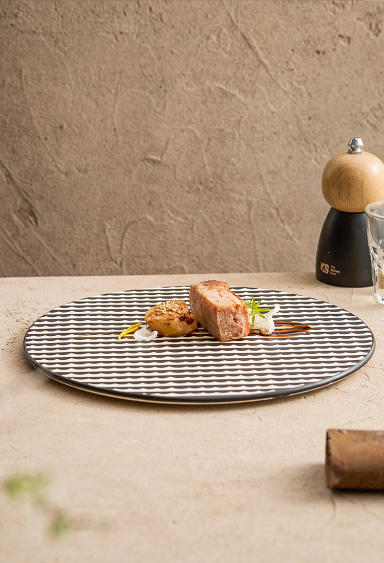 Plated dish with food on a textured surface, pepper grinder, and glass in the background.