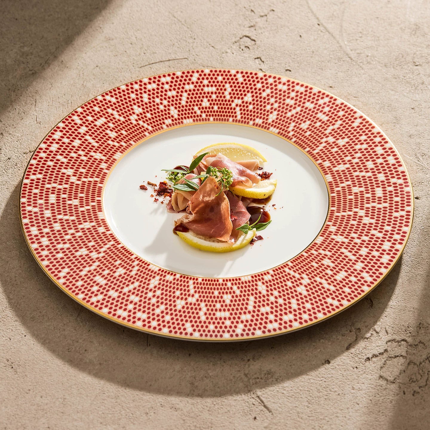Detailed geometric tile pattern in red and coral on an artisanal ceramic plate rim.
