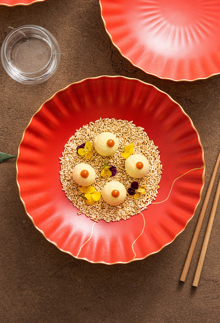 Red plate with a dish of food on a brown surface