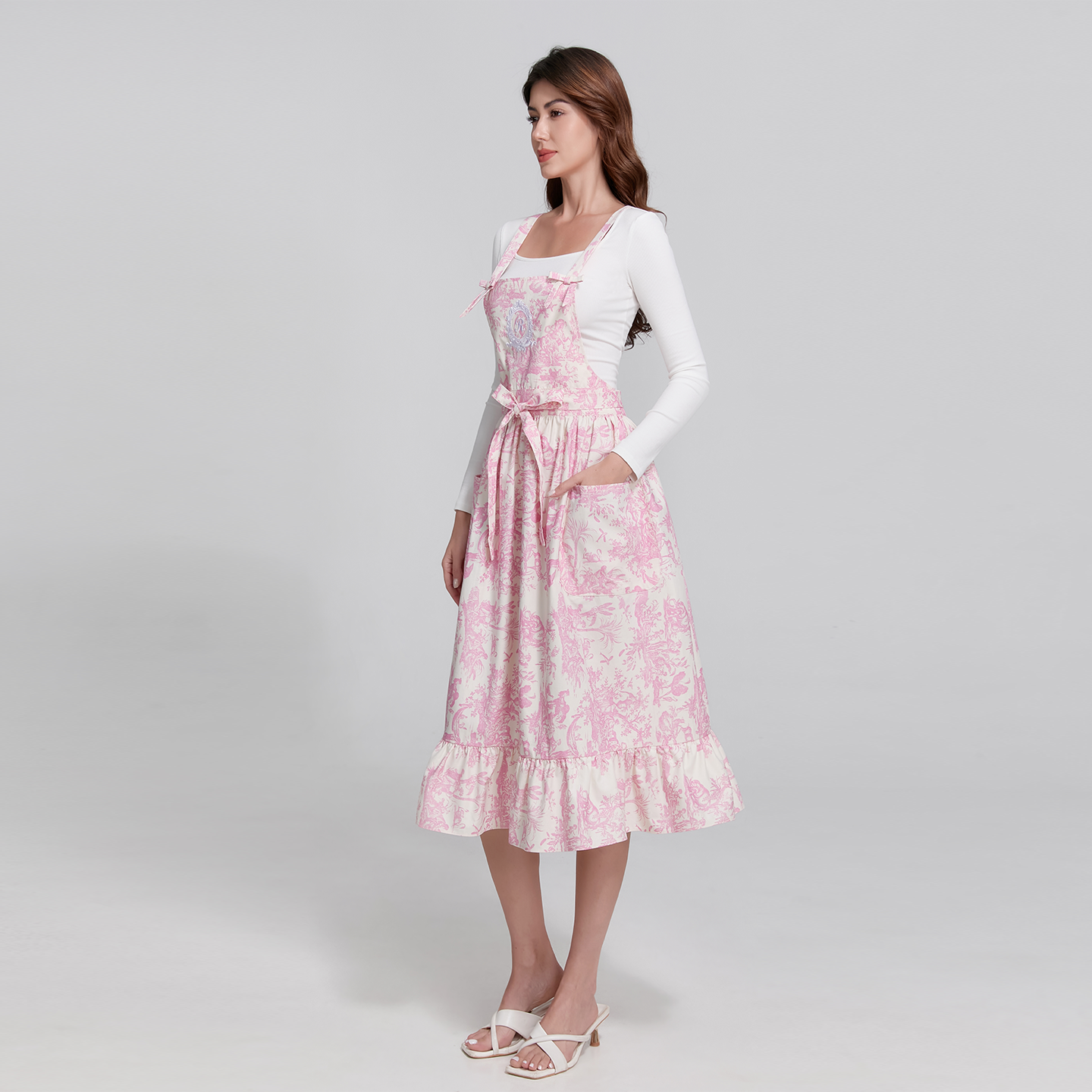 Full-length view of a feminine 40-inch pink apron with frill hem accents and a waist-tie ribbon.