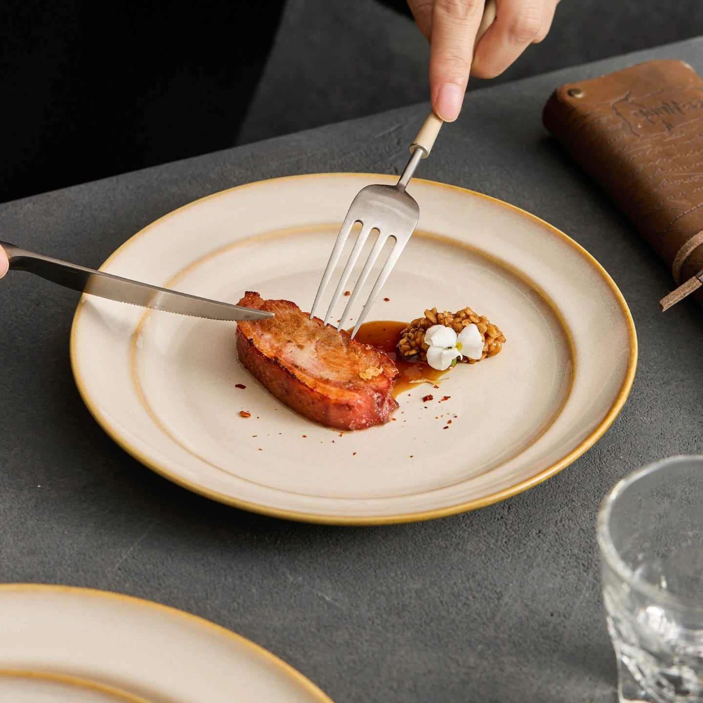 Gourmet plating of seared meat and reduction sauce on a cloud-patterned artisan plate.