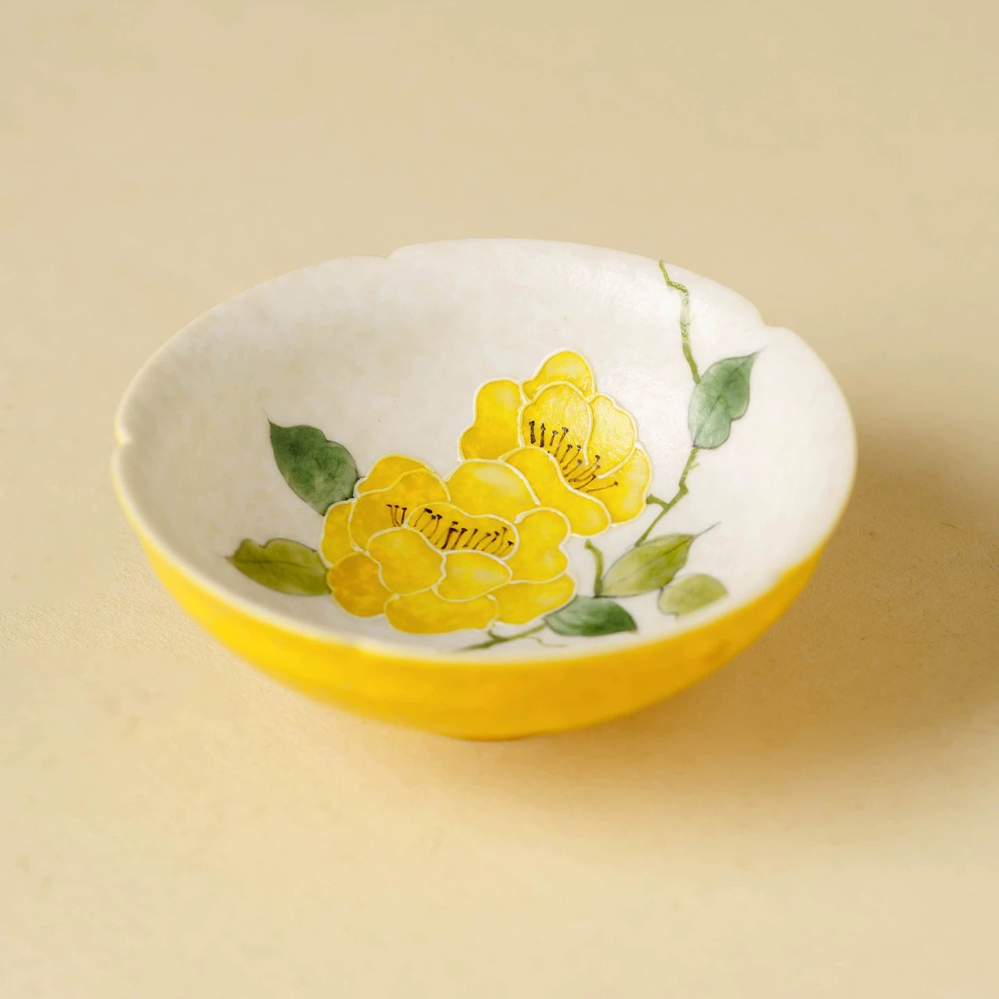 Hand-painted yellow blossom porcelain tea cup with a scalloped flower-mouth rim.