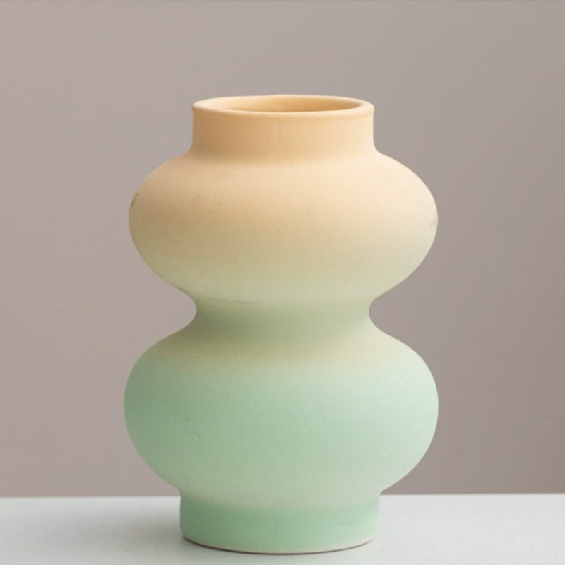 Two-toned ceramic vase with beige top and green bottom on a plain background