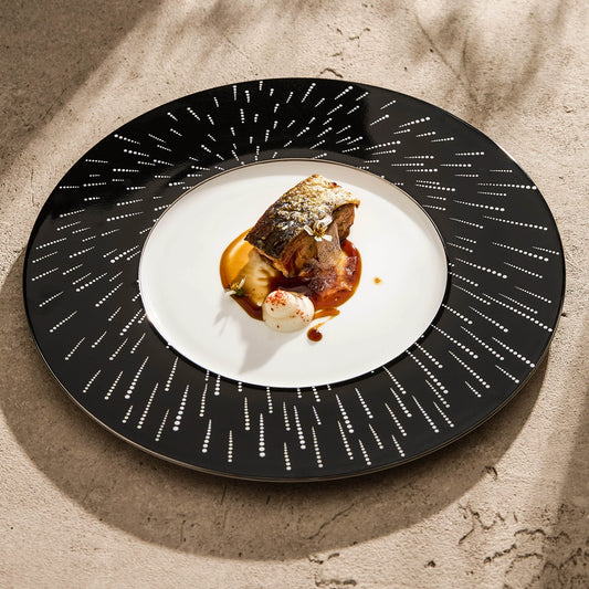 High-contrast table setting with a midnight-black "Starry Night" artisan dinner plate.