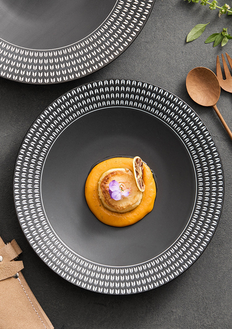 High-end restaurant-style plating using a sculptural matte black plate for artistic food display.