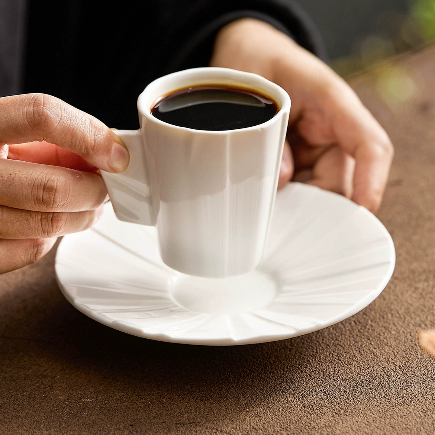 High-fired porcelain coffee cup with origami-inspired handle.