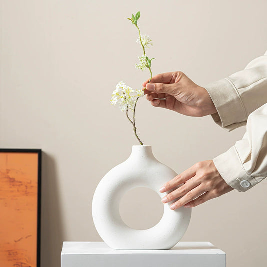 Set of three white ceramic vases with circular hollow design

