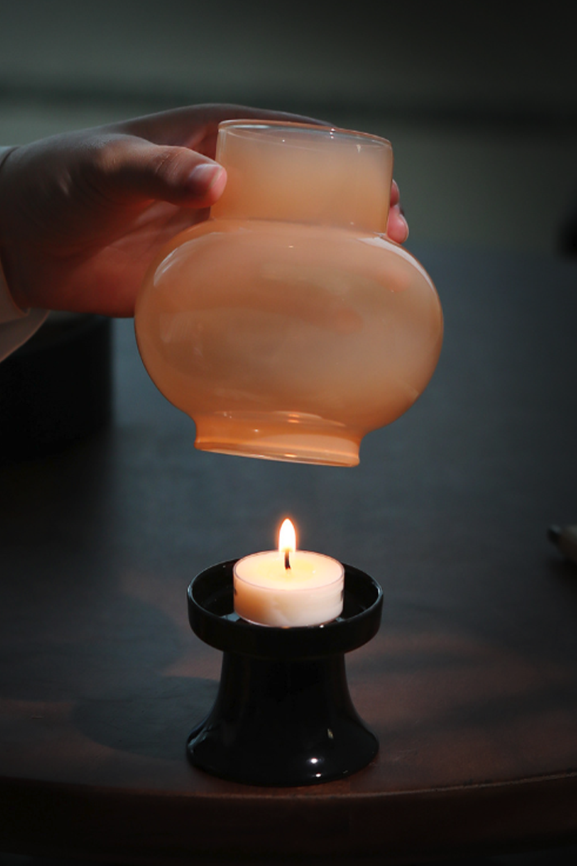 Jade glass lantern by GOSEUNG glowing softly with scented warmth.