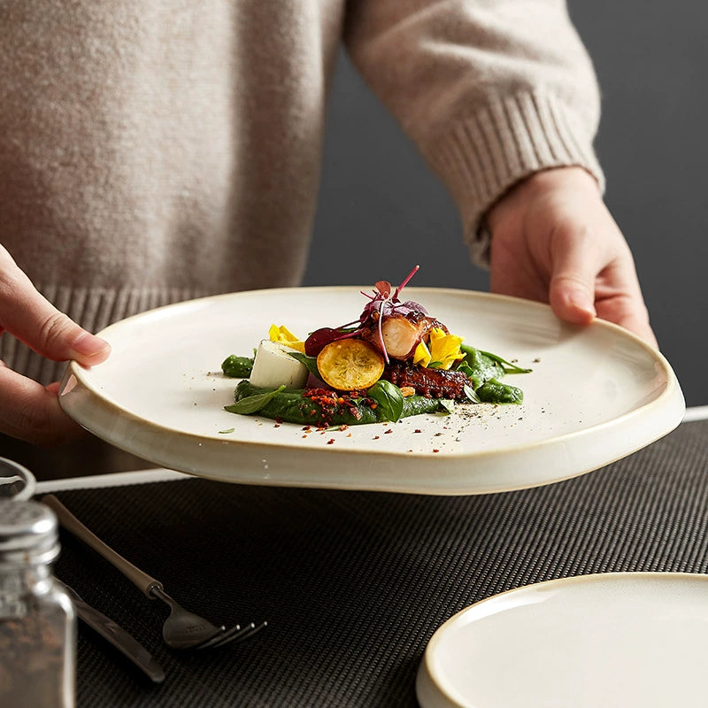 Person holding a plate with a gourmet dish featuring greens and vegetables.