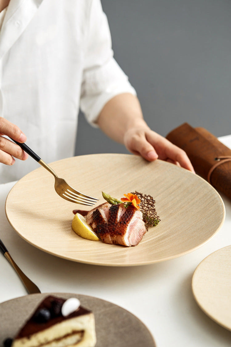 Person holding a plate with a dish of meat and vegetables, using a fork.