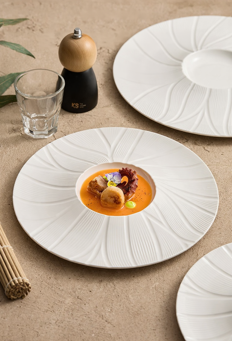 Minimalist ceramic plate with recessed center for chef dishes.
