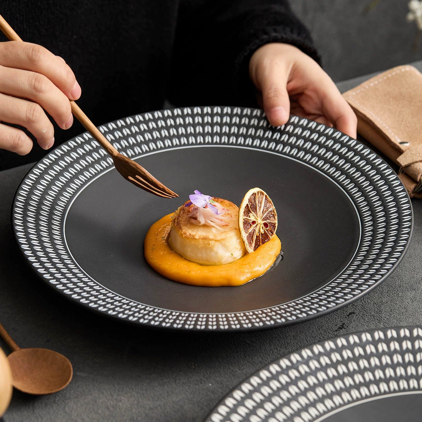 Minimalist matte black pasta plate featuring a sophisticated ivory chain-link geometric border.