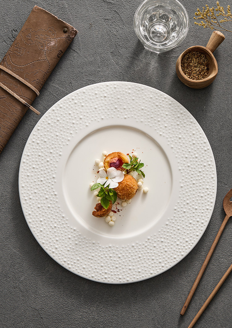 Minimalist wide-rimmed ceramic plate with sesame point speckle-effect glaze.