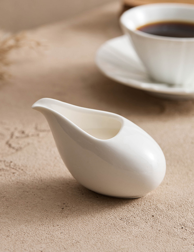 Modern ceramic creamer for serving milk or cream in a minimalist cafe setting.