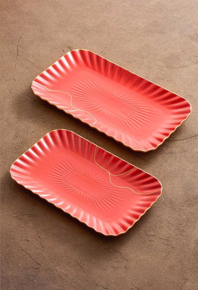 Two pink ceramic trays with textured design on a brown surface