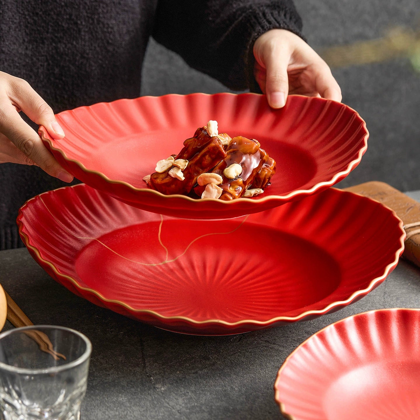 Red ceramic plate with scalloped edge holding food, placed on a dark surface.