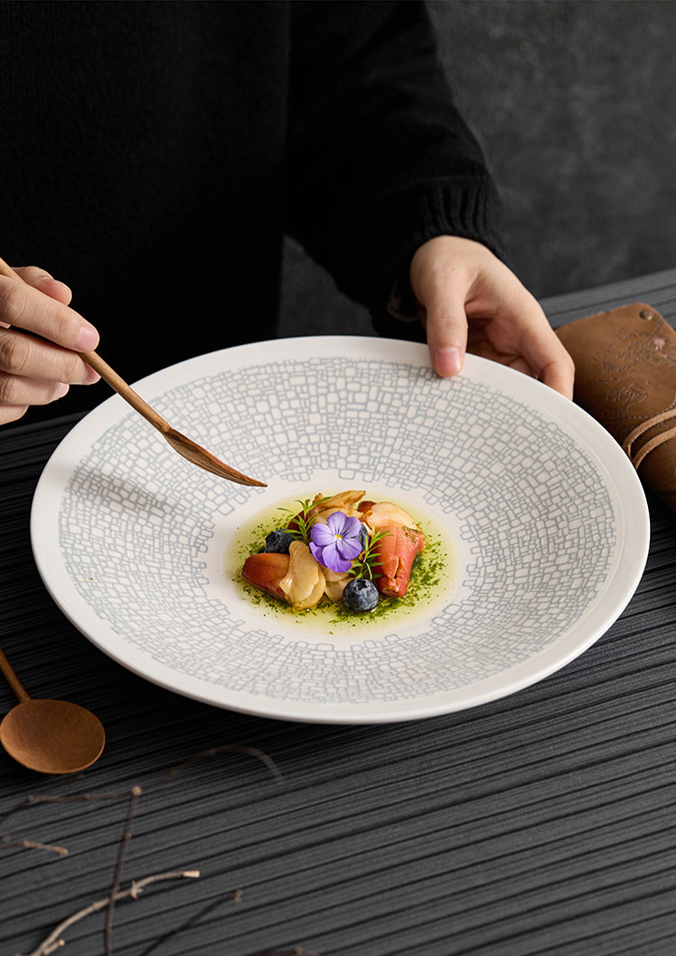 Modern white ceramic plate with a textured blue geometric border for hostings.