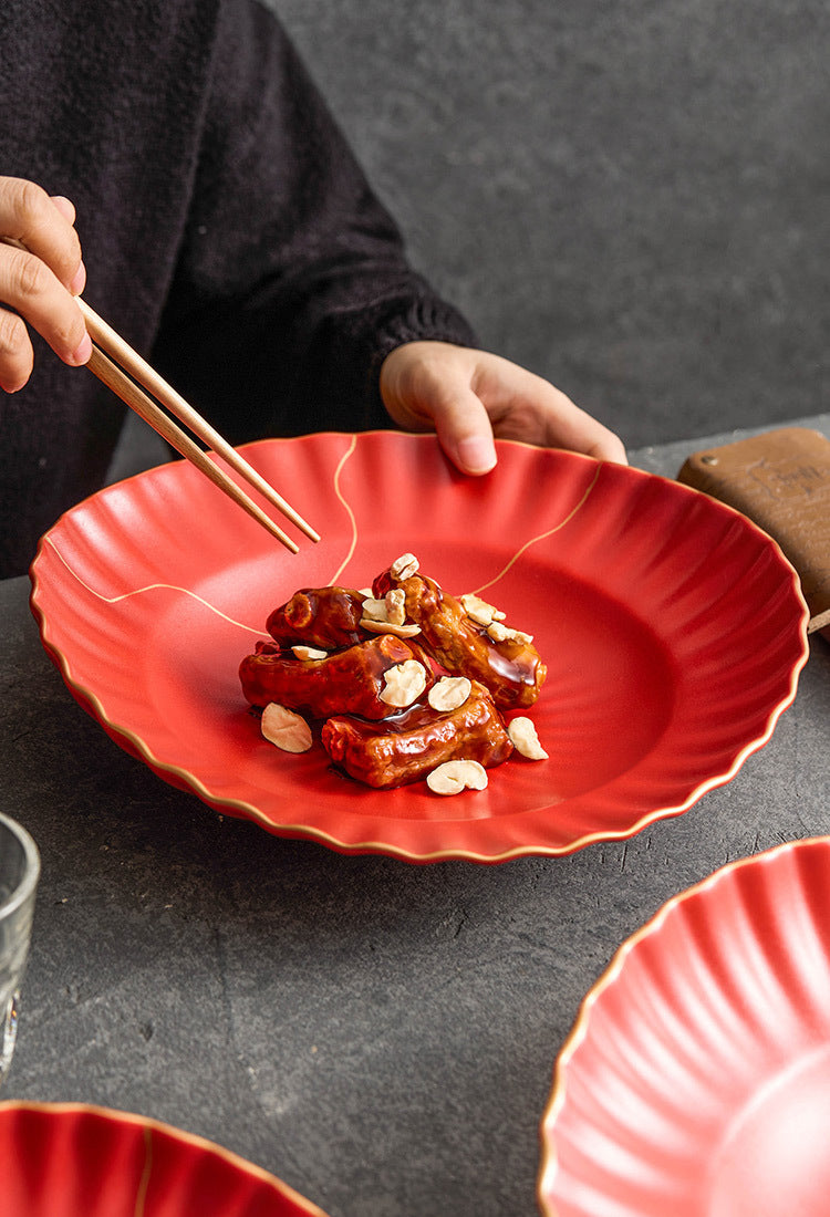Red plate with food and chopsticks on a dark surface