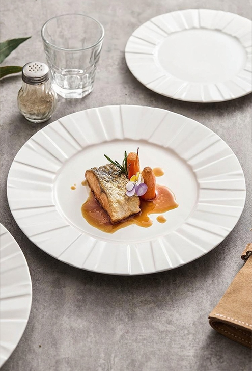 Origami-inspired white porcelain dinner plate with pleated texture for modern minimalist table setting