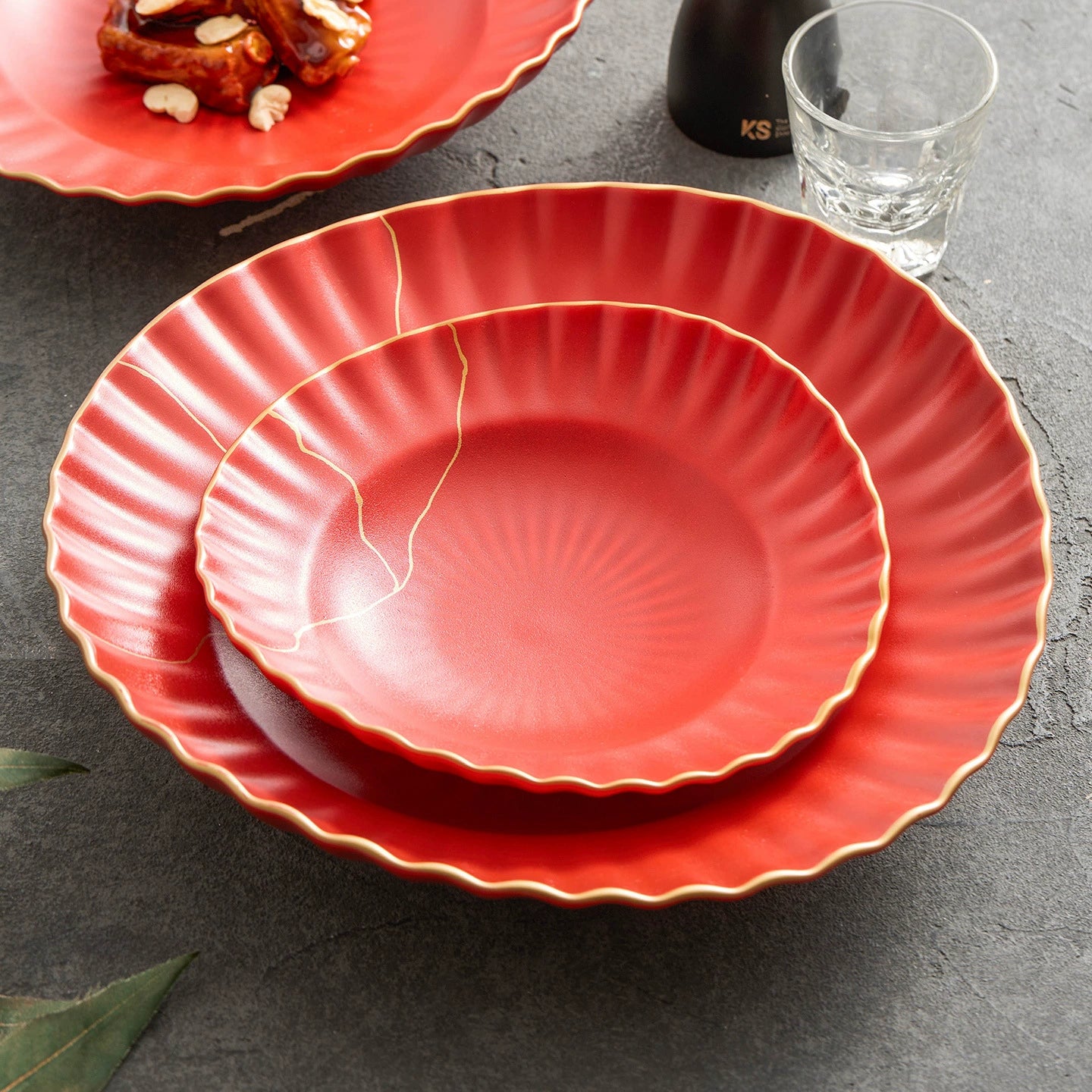 Red ceramic plates with gold rim on a dark surface