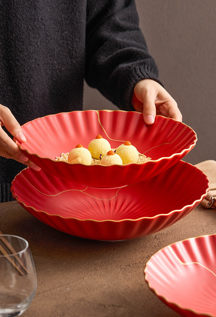 Red scalloped-edge bowl being held by a person with food inside on a brown surface.