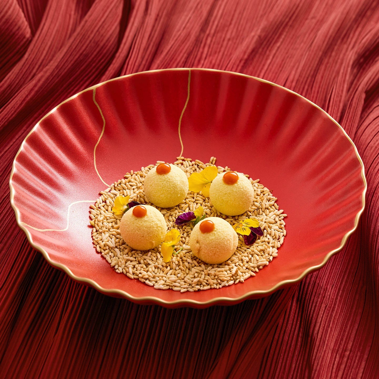 Decorative plate with spherical treats and seeds on a red fabric background
